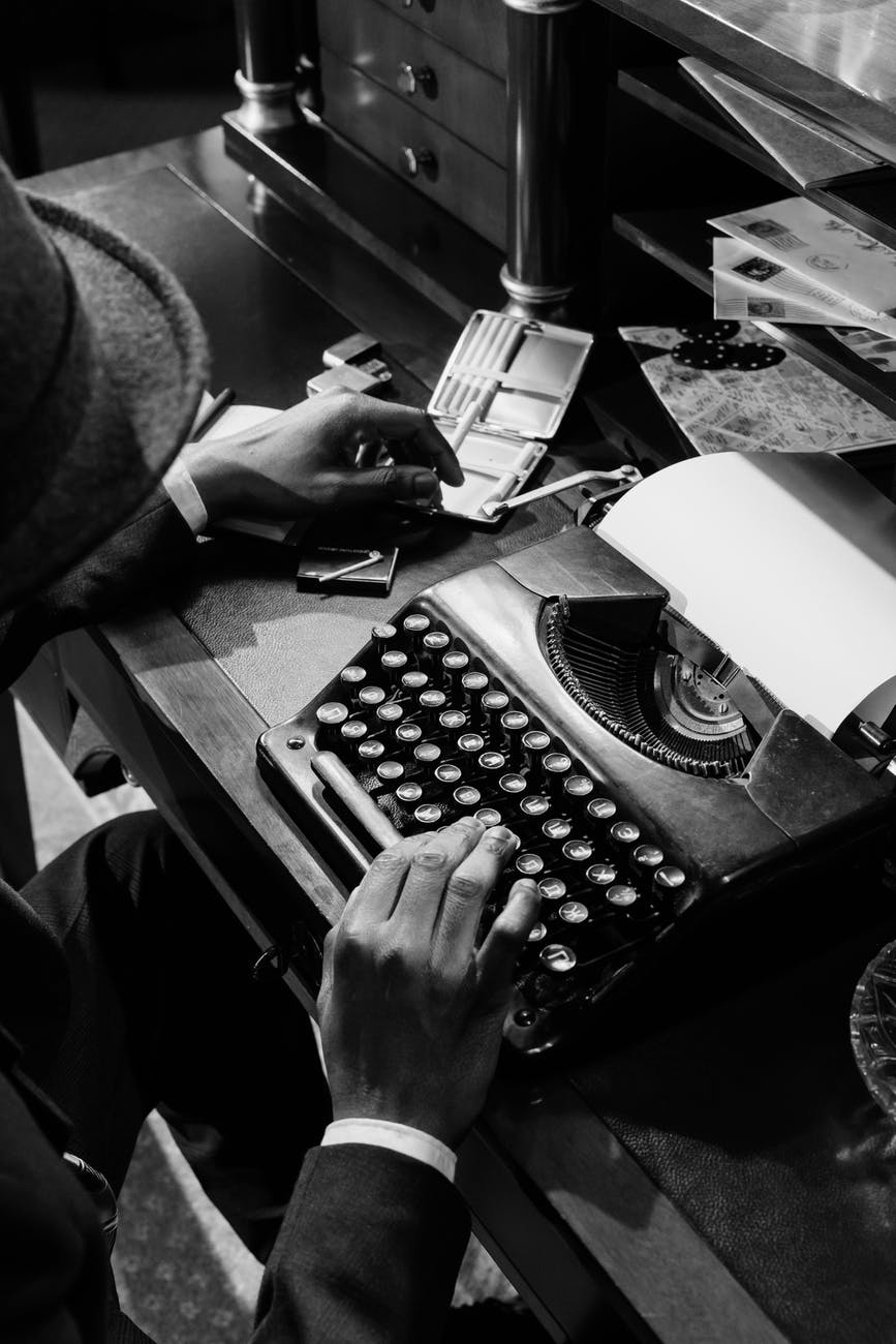 monochrome photo of person using vintage typewriter