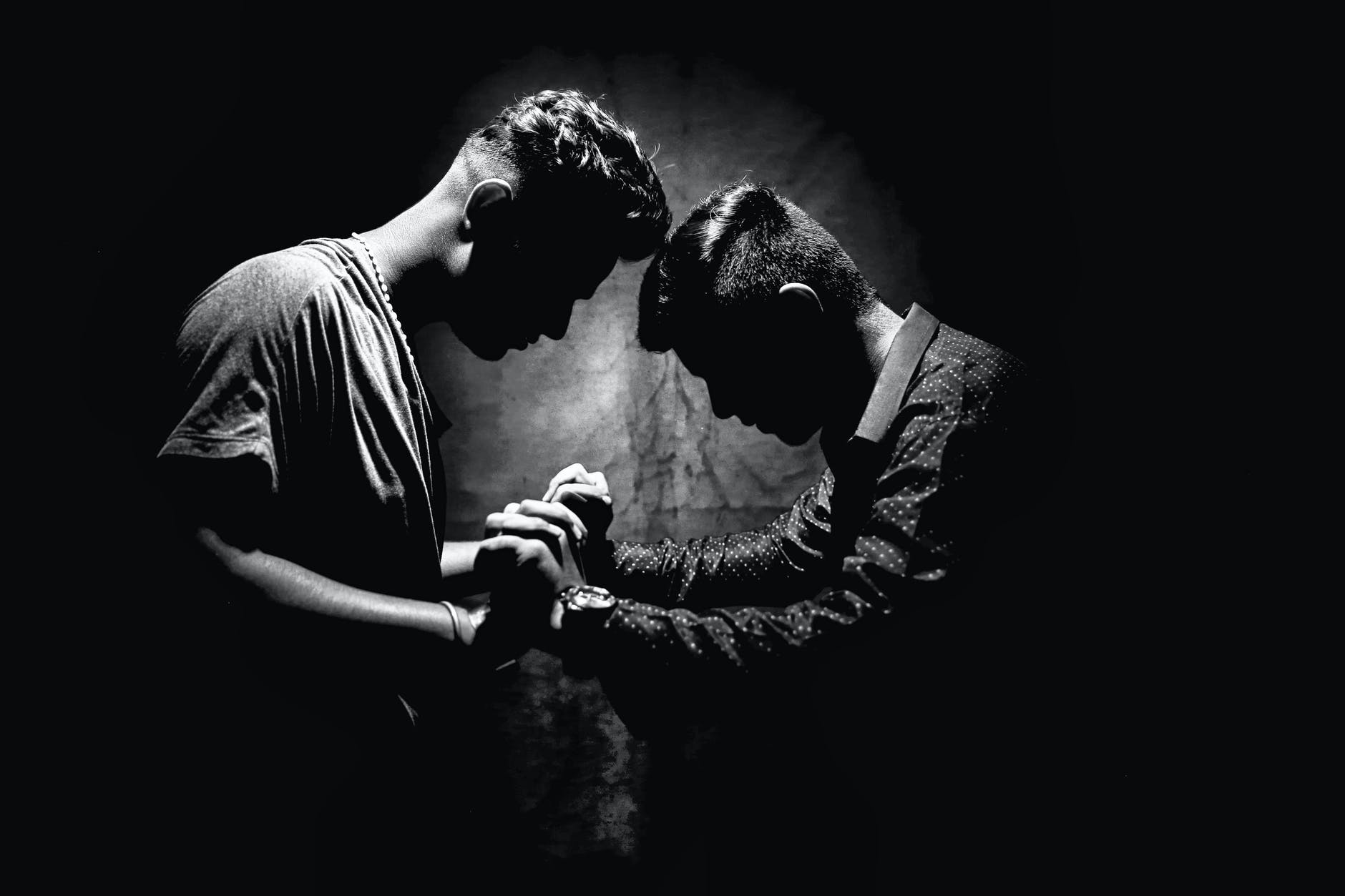 grayscale photo of two men holding hands