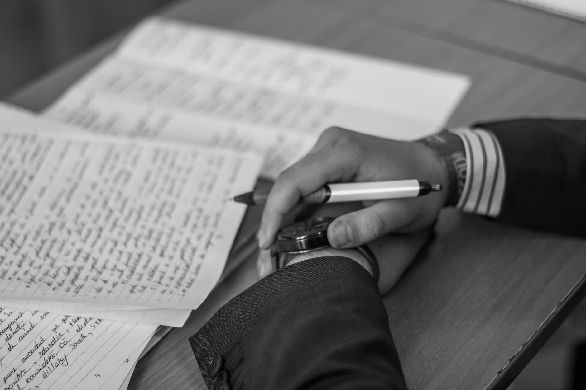 grayscale photography of person holding pen